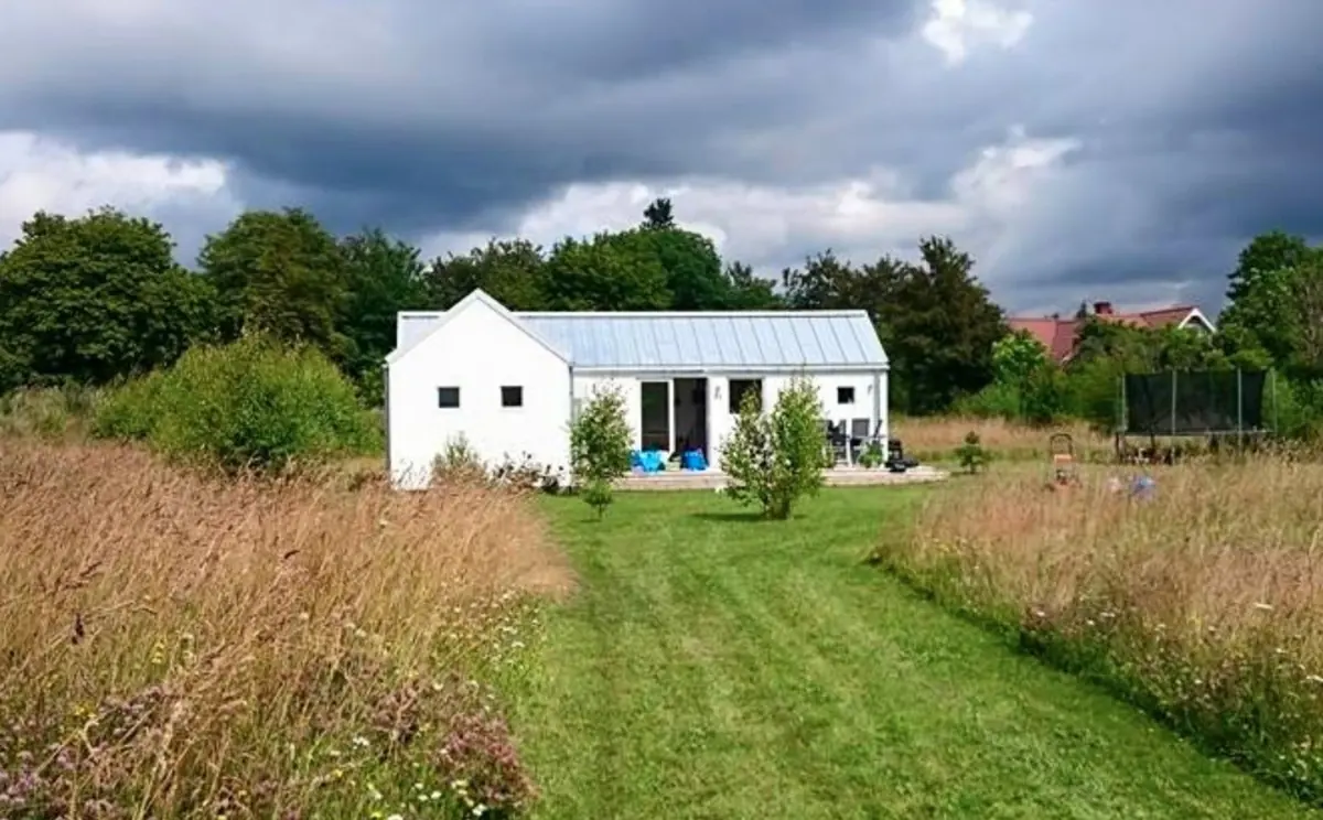 Kronholmen 55, ett vitt hus med sadeltak och plåttak i en sommaräng